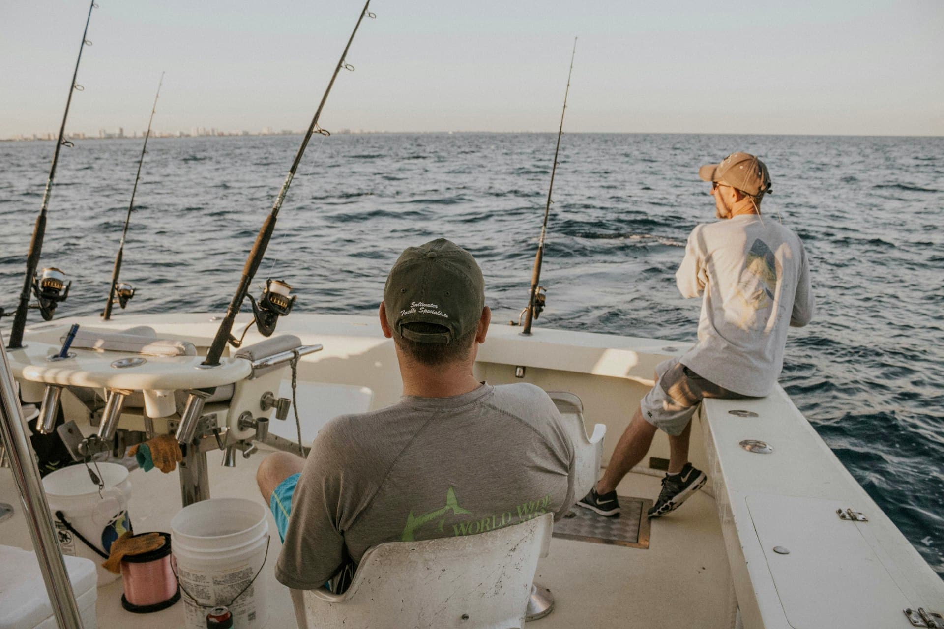 Two guests on the back deck of a fishing charter, watching the rods