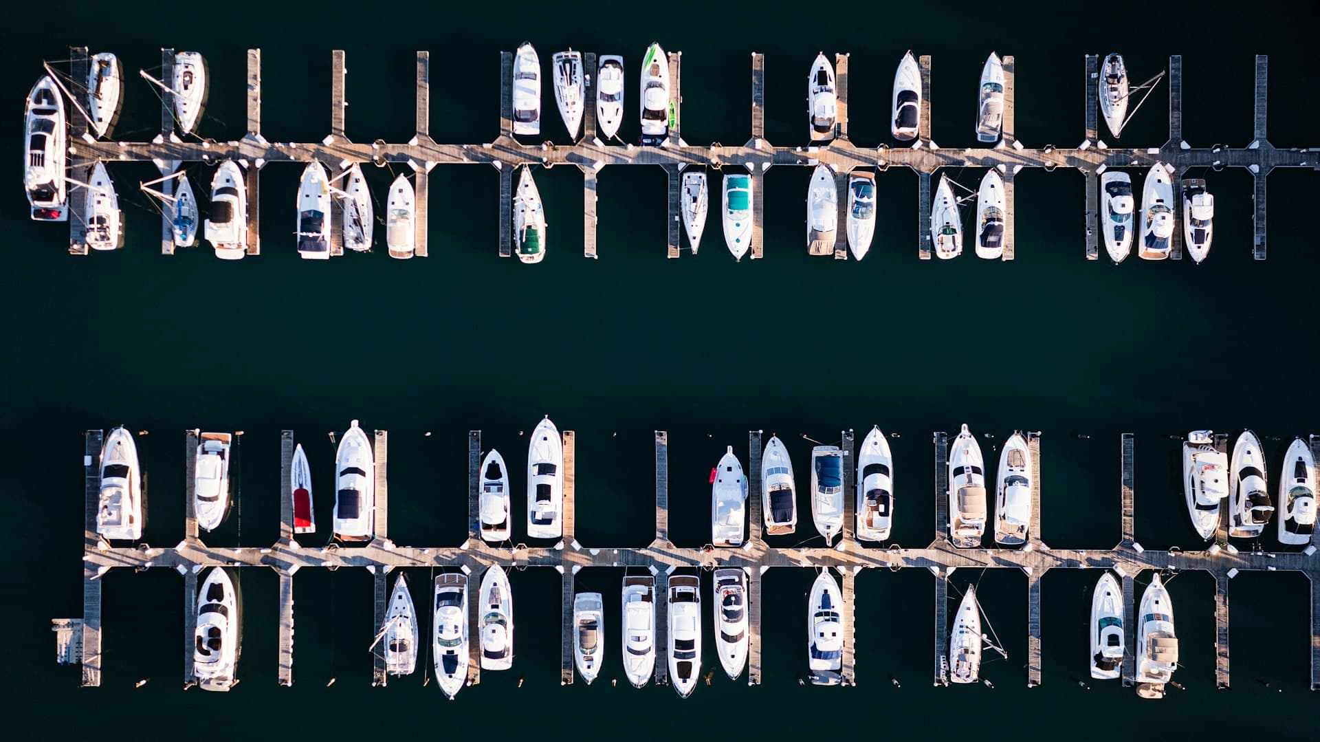 Rows of boats tied up in a marina, seen from above
